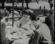 A Close up of Two Women and a Man Having Food and Drink on the Roof Terrace at the Tea..., 1939. Creator: British Pathe Ltd