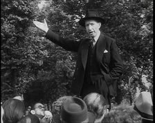 A Close up of a British Man in Dark Suit and Hat Declaiming Before a Crowd from a Raised..., 1938. Creator: British Pathe Ltd