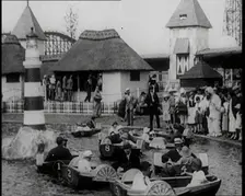 A Crowd of People Standing By a Boating Lake and Watch Other People in Paddle Boats, 1924. Creator: British Pathe Ltd