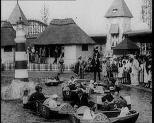 A Crowd of People Standing By a Boating Lake and Watch Other People in Paddle Boats, 1924. Creator: British Pathe Ltd