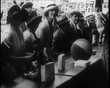 A Crowd of People Playing a Game Where They Have to Pop a Balloon By Turning a Handle, 1924. Creator: British Pathe Ltd