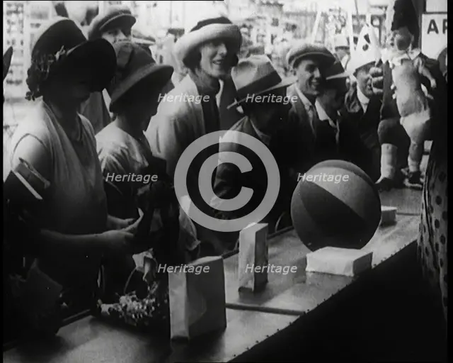 A Crowd of People Playing a Game Where They Have to Pop a Balloon By Turning a Handle, 1924. Creator: British Pathe Ltd.