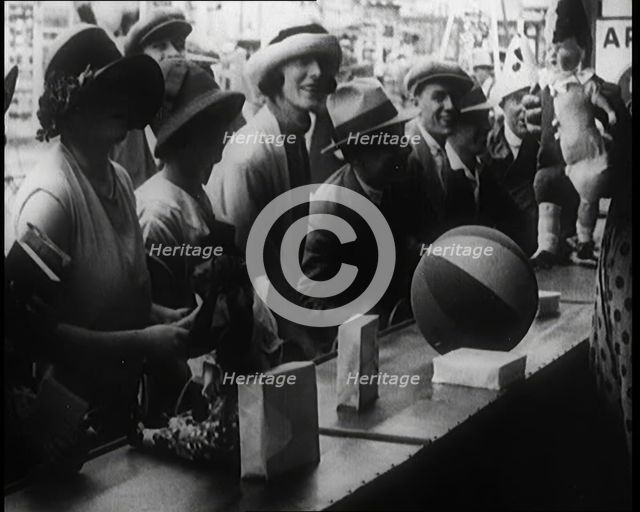 A Crowd of People Playing a Game Where They Have to Pop a Balloon By Turning a Handle, 1924. Creator: British Pathe Ltd.