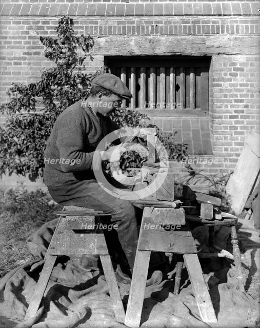 A craftsman shaping a brick on a bench at Great Dixter, Northiam, East Sussex, 1919. Artist: Nathaniel Lloyd