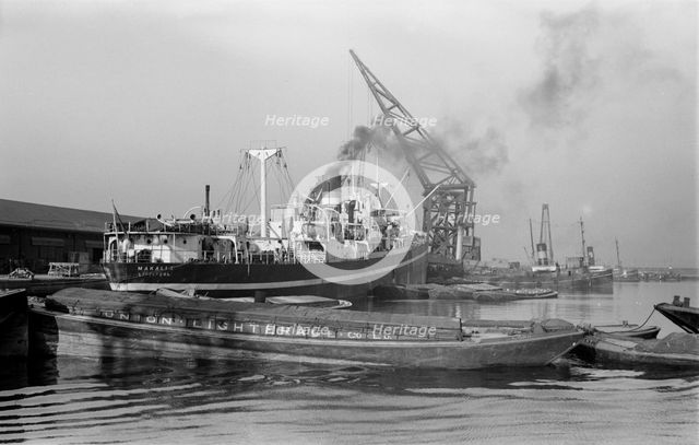 A crane unloads cargo from the 'Makalla' in Tilbury Docks, Essex, c1945-c1965. Artist: SW Rawlings
