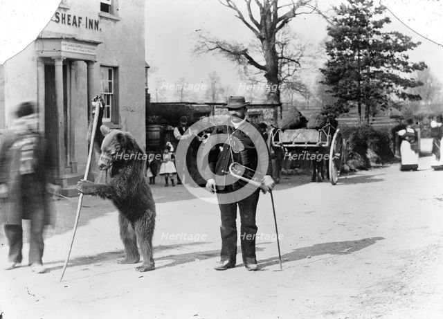 A dancing bear and owner performing outside an inn, Oxfordshire, c1900. Artist: Henry Taunt