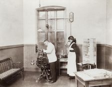 A dentist and his nurse give a schoolboy his treatment, 1910s