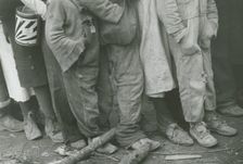 A detailed shot of flood refugees feet showing their shoes; Forrest City, Arkansas, 1930s. Creators: Farm Security Administration, Walker Evans