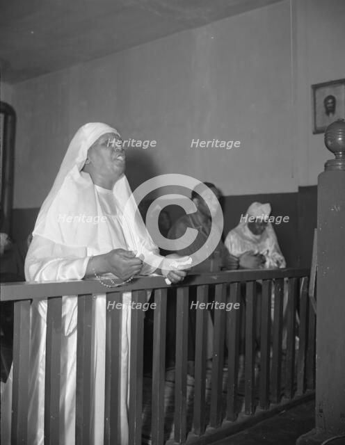 A disciple of the St. Martin's Spiritual Church praying before the altar..., Washington, D.C., 1942. Creator: Gordon Parks.