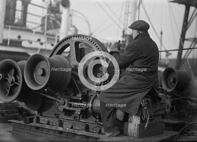 A docker operates a winching gear in London Docks, London, c1945-c1965.  Artist: SW Rawlings