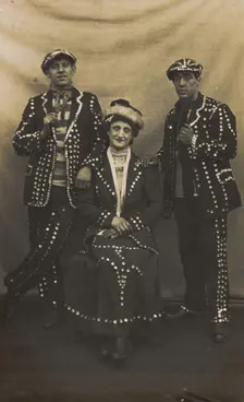 A drag pearly queen and her two kings pose for a group portrait, (between 1910 and 1919?). Creator: Unknown