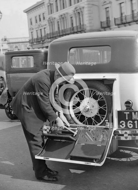 A driver opening the fitted toolkit of his Ford Model A at the Southport Rally, 1928. Artist: Bill Brunell.