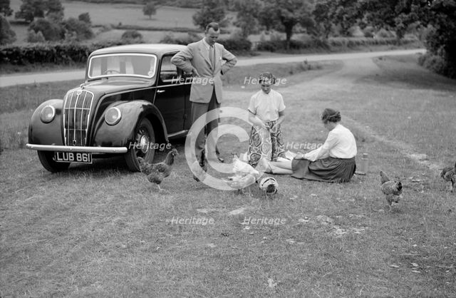 A family group feed chickens beside their car, c1945-c1965. Artist: SW Rawlings