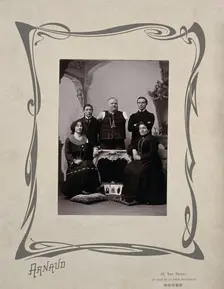 A family portrait: a man without arms and legs poses on a table surrounded by family, 20th Century. Creator: Unknown