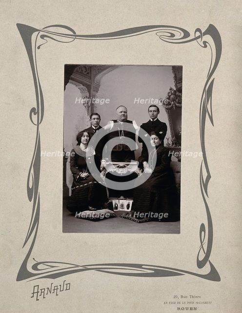 A family portrait: a man without arms and legs poses on a table surrounded by family, 20th Century. Creator: Unknown.