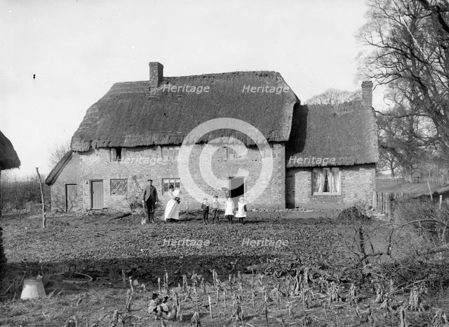 A family pose outside their thatched cottage at Hatford, Oxfordshire, c1860-c1922. Artist: Henry Taunt