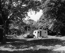 A family relaxing on holiday with their 1951 Vauxhall Wyvern and caravan, (1951?)