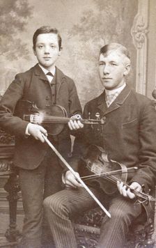 A father and son posing with their violins