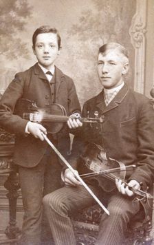 A father and son posing with their violins. Creator: Unknown