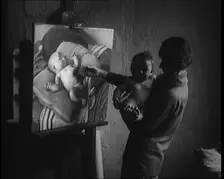 A Female Civilian Holding a Nude Child in Her Arms in front of a Painting of a Nude Child, 1920. Creator: British Pathe Ltd