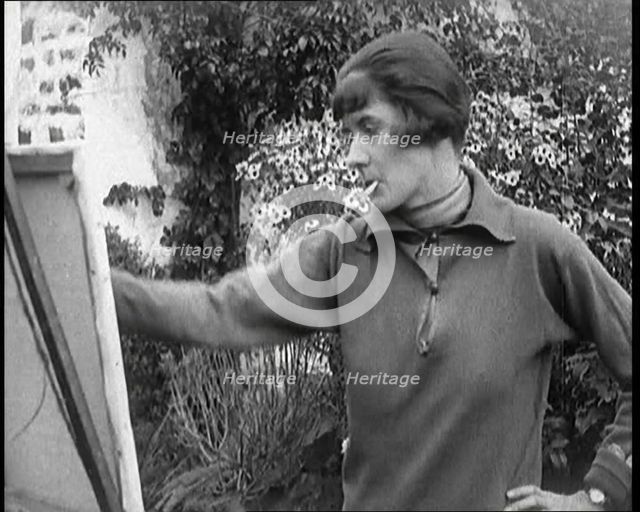 A Female Civilian Painting at an Easel Outdoors Smoking a Cigarette, 1920. Creator: British Pathe Ltd.