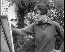 A Female Civilian Painting at an Easel Outdoors Smoking a Cigarette, 1920. Creator: British Pathe Ltd