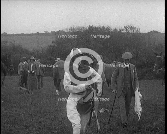 A Female Civilian Wearing a Jockey's Outfit Walking on a Horse Racing Track Watched by a..., 1920. Creator: British Pathe Ltd.