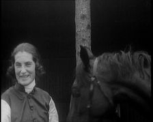 A Female Civilian Wearing a Jockey's Outfit Removing Her Hat in Front of Her Horse and..., 1920. Creator: British Pathe Ltd