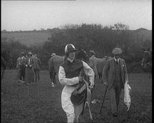 A Female Civilian Wearing a Jockey's Outfit Walking on a Horse Racing Track Watched by a..., 1920. Creator: British Pathe Ltd