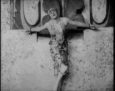 A Female Actor Chained to a Wall for a Performance, She Is Wearing a Glamorous Dress, 1922. Creator: British Pathe Ltd