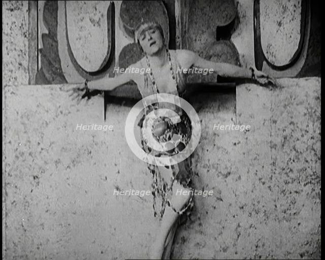 A Female Actor Chained to a Wall for a Performance, She Is Wearing a Glamorous Dress, 1922. Creator: British Pathe Ltd.