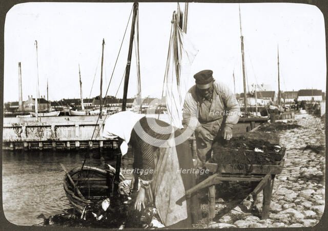 A fisherman and his wife with nets and a wheelbarrow, Borstahusen, Landskrona, Sweden, 1905. Artist: Unknown