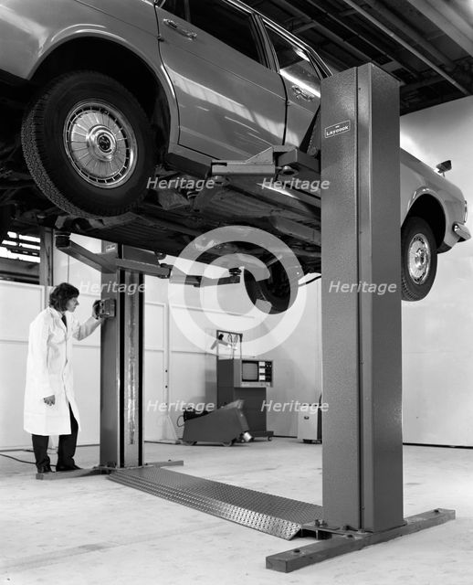 A Ford Zodiac on a Laycock asymmetric lift, 1972.  Creator: Michael Walters.