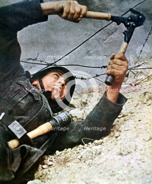 A German soldier cutting through barbed wire during an assalt, 1942. Artist: Unknown