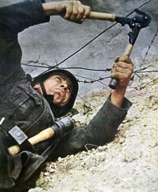 A German soldier cutting through barbed wire during an assalt, 1942
