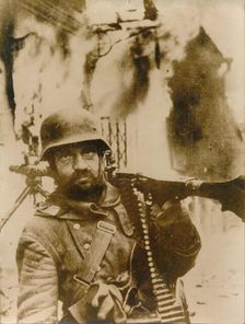 A German soldier standing in a burning Russian village