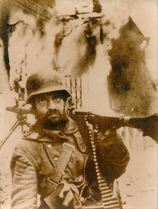 A German soldier standing in a burning Russian village. Creator: Unknown
