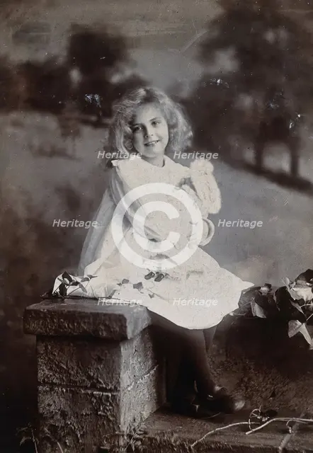 A girl, holding a doll, sitting on a wall, c1890s. Creator: Lock & Whitfield.