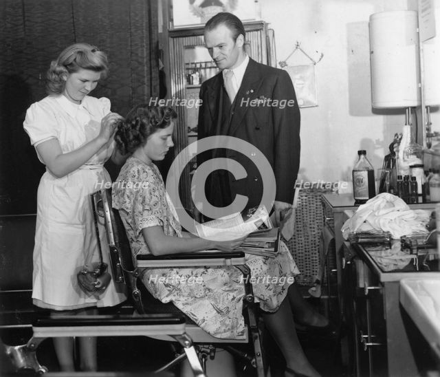 A girl passing the test to qualify as a hairdresser before a male inspector, Sweden, c1940-1959. Creator: Unknown.