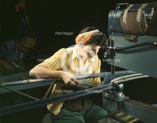 A girl riveting machine operator at the Douglas Aircraft Company plant..., Long Beach, Calif. , 1942 Creator: Alfred T Palmer.
