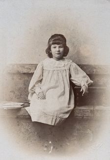 A girl, sitting on a stone bench with a fan folded at her side, c1890s. Creator: Arthur Reston
