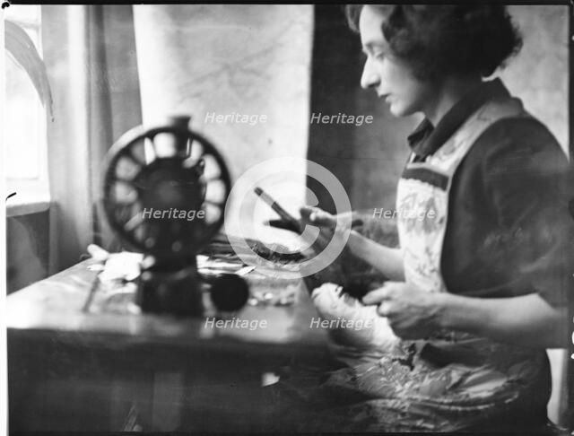 A glover or glove maker working at a sewing machine, Woodstock, Oxfordshire, 1920-40. Creator: George R Long.