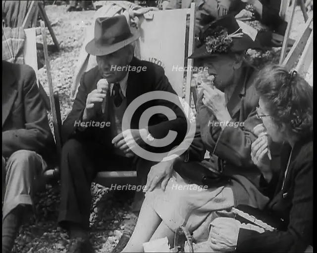 A Group of Two Men and Two Women Sitting on Deckchairs on the Beach at  Brighton and Eating..., 1939 Creator: British Pathe Ltd.