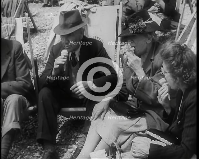A Group of Two Men and Two Women Sitting on Deckchairs on the Beach at  Brighton and Eating..., 1939 Creator: British Pathe Ltd.