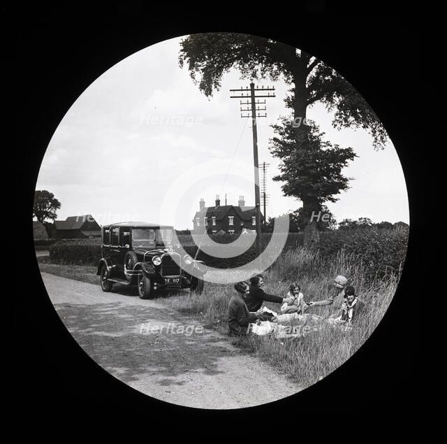 A group of women and girls having a picnic near a parked car at the side of a road..., 1920s-1930s. Creator: Norman Kingsley Harrison.