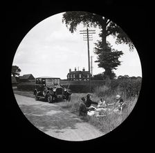 A group of women and girls having a picnic near a parked car at the side of a road..., 1920s-1930s. Creator: Norman Kingsley Harrison