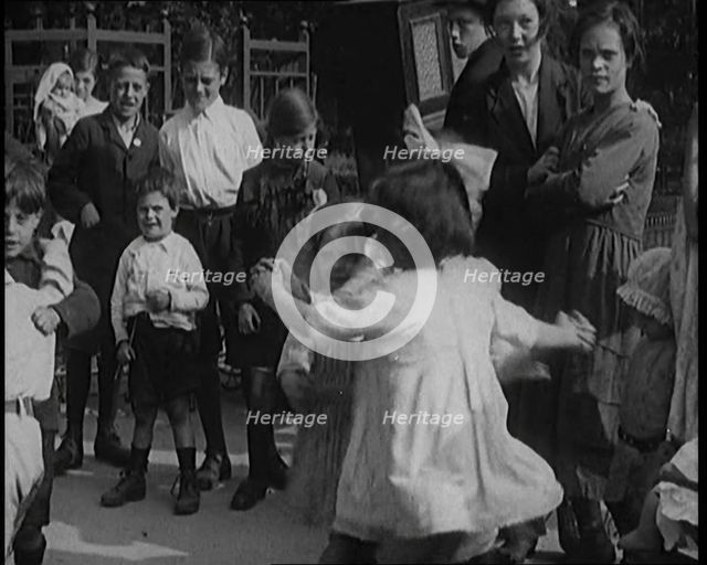 A Group of Civilian Children Dancing in Front of a Hurdy Gurdy Watched by a Small Crowd, 1920. Creator: British Pathe Ltd.