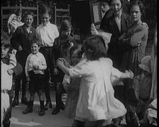 A Group of Civilian Children Dancing in Front of a Hurdy Gurdy Watched by a Small Crowd, 1920. Creator: British Pathe Ltd
