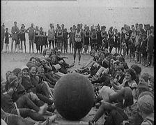 A Group of Female Civilians Exercising with a Large Ball on a Beach, 1920. Creator: British Pathe Ltd