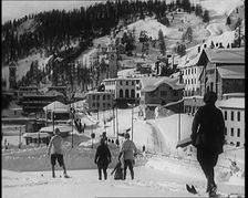 A Group of Female Civilians Skiing down a Snowy Hill with a Picturesque Alpine Village..., 1920. Creator: British Pathe Ltd